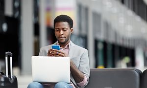 En mann bruker smarttelefonen med en bærbar PC på fanget