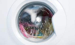 Fargerike klær sentrifugeres inni en vaskemaskin