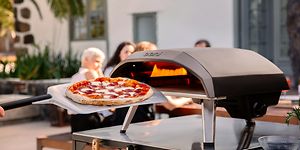 en pizza foran en pizzaovn og mennesker i bakgrunnen