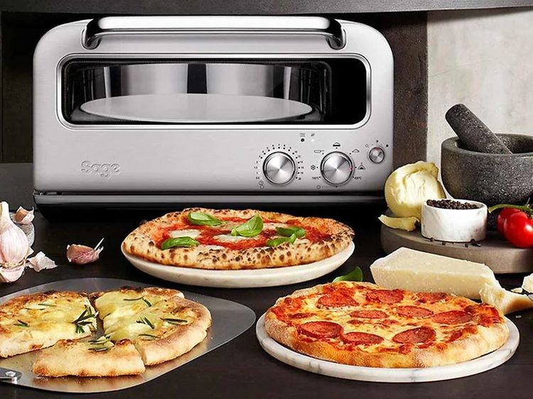 Ulike typer pizza på et bord og en pizzaovn fra Sage i bakgrunnen