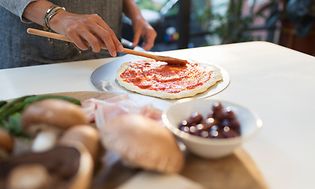 person lager pizza på en kjøkkenbenk