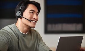 Mann snakker med Jabra Evolve2 ved laptop