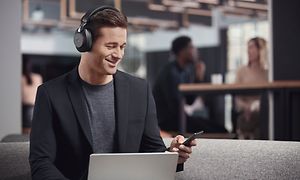 Mann med Jabra Evolve2 85, laptop og mobil