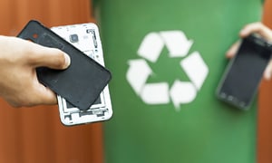 komponenter fra gamle mobiltelefoner foran resirkuleringstegn