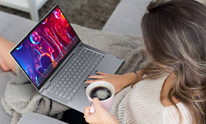 Kvinne sitter med en Lenovo Yoga 7 i fanget