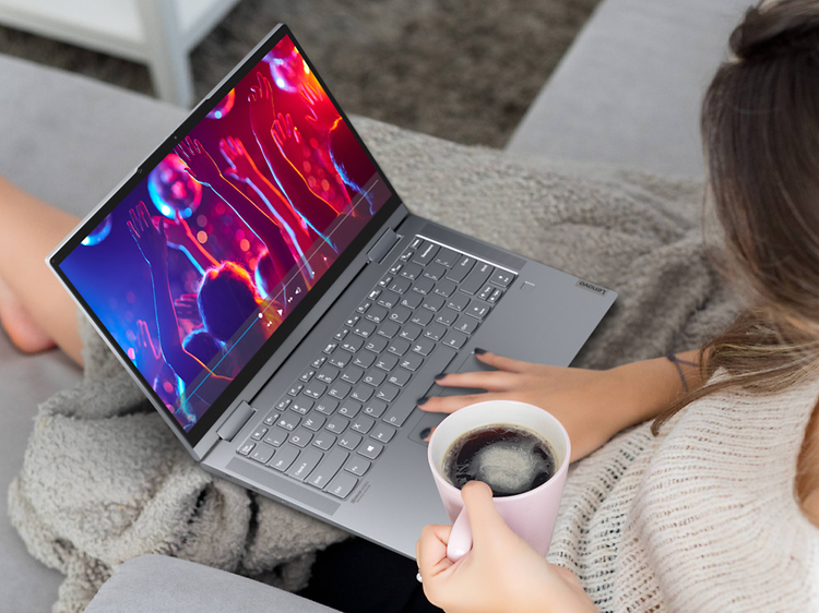 Kvinne sitter med en Lenovo Yoga 7 i fanget