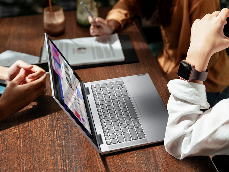 Kvinne sitter på en kafé med en Lenovo Yoga 7 åpen foran seg