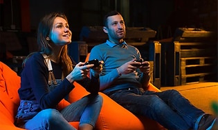 mann og kvinne sitter sammen og holdere gaming-kontroller i hendene