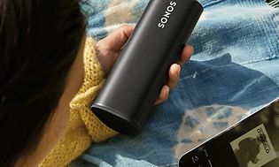 Kvinne holder Sonos Roam og mobil