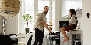 Father talking to daughter whilst empFar snakker med datteren sin mens han tømmer oppvaskmaskinentying the dishwasher