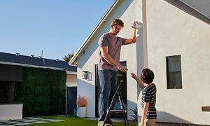 Mann monterer Arlo-kamera på hus