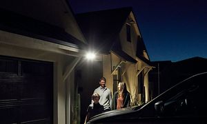 Familie under Arlo Floodlight-kamera foran hus