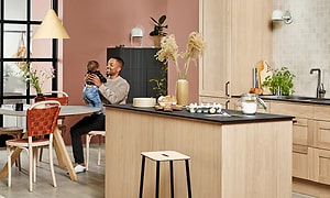 Epoq Shaker Natural Oak kjøkken med kjøkkenøy og mann som holder ungt barn