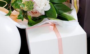 Blomsterbukett og hvit gaveboks med rosa bånd