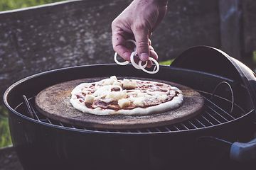 Person som putter topping på en pizza