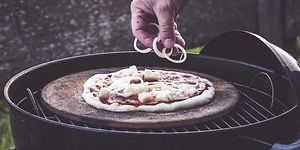 Person som putter topping på en pizza