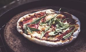 Pizza med topping på en pizzasten