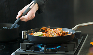 person lager mat med Fiskars Rotisser kaserolle og stekepanne