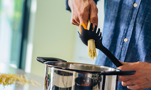 person putter spaghetti i en kaserolle ved hjelp av utstyr fra Fiskars