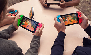 Nintendo Switch -fire mennesker sitter og gamer sammen med håndholdte enheter