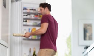 En mann tar mat ut fra kjøleskapet