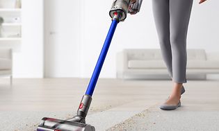 En dame som rengjør et teppe med en Dyson V11 trådløs støvsuger