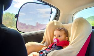 baby i bilsete med solskjerm på vindu