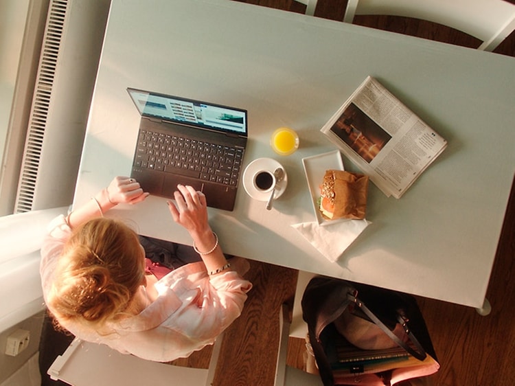 Kvinne bruker bærbar PC mens hun spiser lunsj