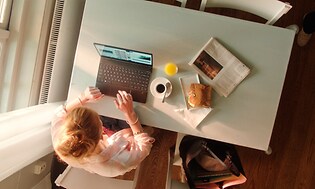Kvinne bruker bærbar PC mens hun spiser lunsj