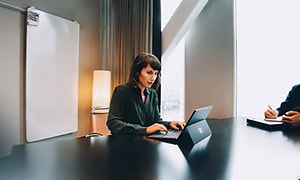 Kvinne bruker en windows pc i et stort møterom