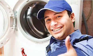 Mann med caps smiler og viser tommel opp foran vaskemaskin