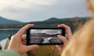 Kvinne tar bilde av innsjø med mobil