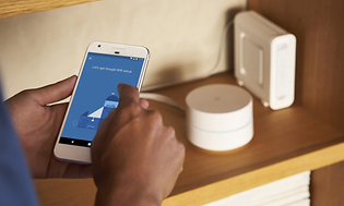 Mann installerer Google mesh-nettverk med telefon