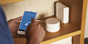 Mann installerer Google mesh-nettverk med telefon
