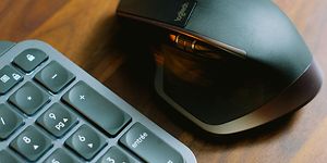 Svart datamus og tastatur på et trebord