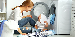 Kvinne og baby har det gøy ved en vaskemaskin