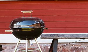 En grill foran et rødt hus