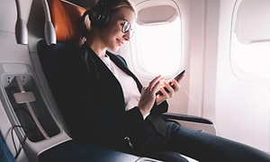 kvinne slapper av på fly med støykansellerende hodetelefoner
