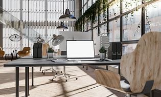 Et lyst kontor med en stor bærbar datamaskin på et skrivebord