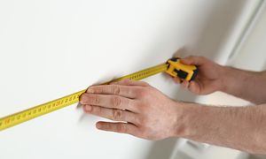 En hånd som gjør oppmålinger på en vegg