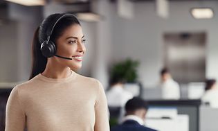 Kvinne smiler mens hun har på seg headset på et kontor