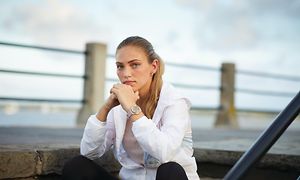 Kvinne som sitter på trapper ved havet