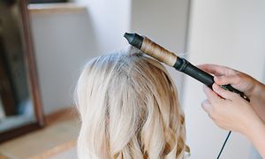 Blond jente får håret sitt krøllet med en krølltang