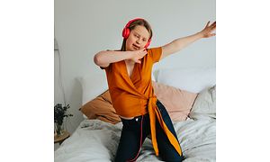 Jente som danser i sengen og har på røde hodetelefoner