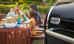 weber pelletsgrill og en familie som spiser i bakgrunnen