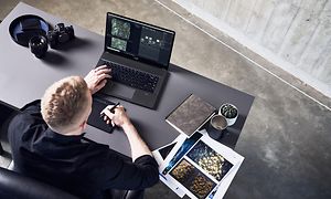 Mann som sitter ved skrivebord og jobber på en MSI Creator Z16P 