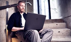 Mann som sitter med en MSI Creator Z16P i en trapp