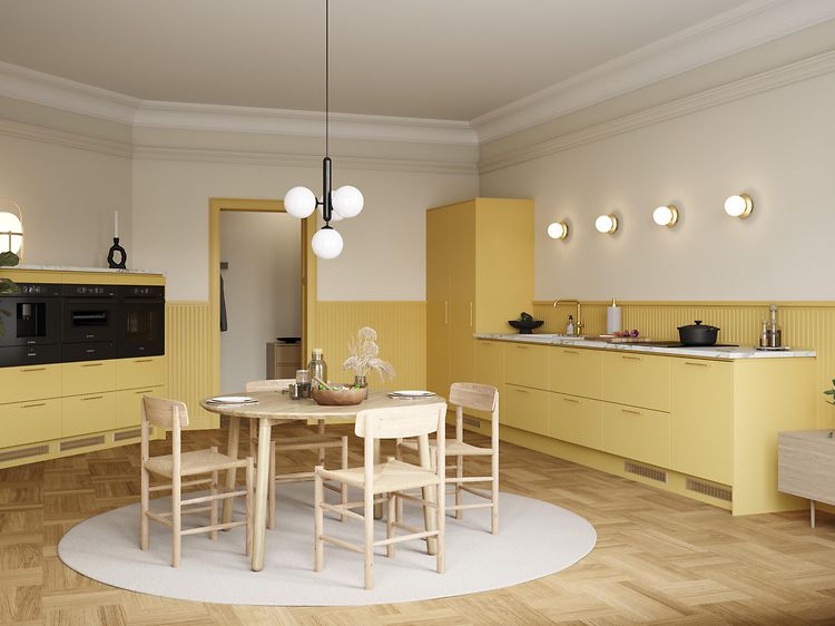 Yellow Epoq Trend Mellow-kjøkken, med benkeplate i marmorlaminat, integrert stekeovn og kaffetrakter, spisebord og stoler.