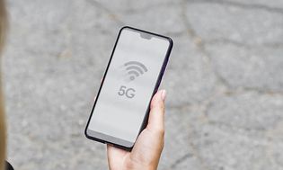 en kvinne ser på smarttelefonen sin med 5G