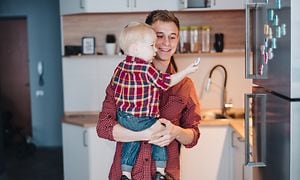 Mann som holder en liten gutt foran et rustfritt kjøleskap